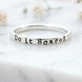 Silver ring with 'Do it Scared' engraving on a light background