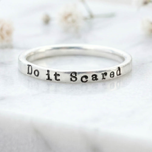 Silver ring with 'Do it Scared' stamped on a light background