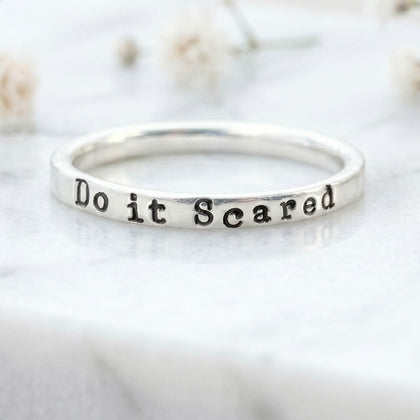 Silver ring with 'Do it Scared' stamped on a light background