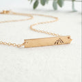 Gold You will move mountains necklace with a bar pendant on a light background