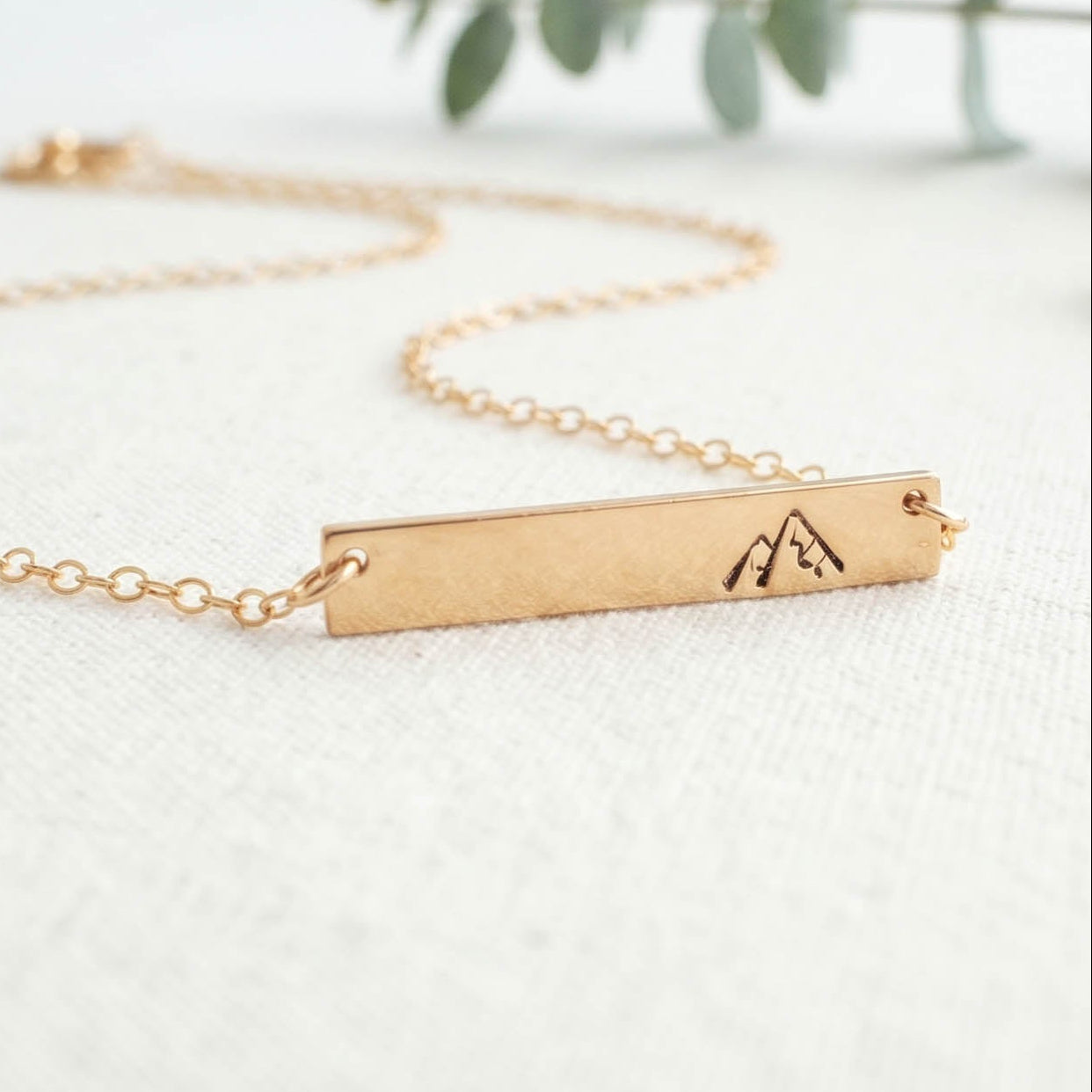 Gold You will move mountains necklace with a bar pendant on a light background