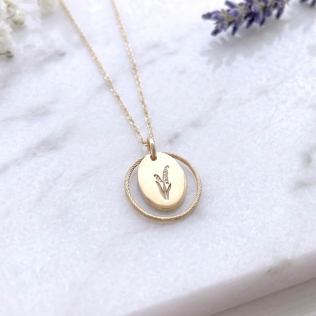 lily of the valley gold filled july birth flower necklace on a marble surface