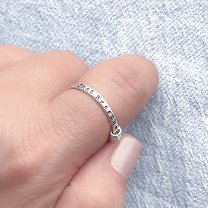 image of sterling silver ring stamped with Just Breathe on a hand