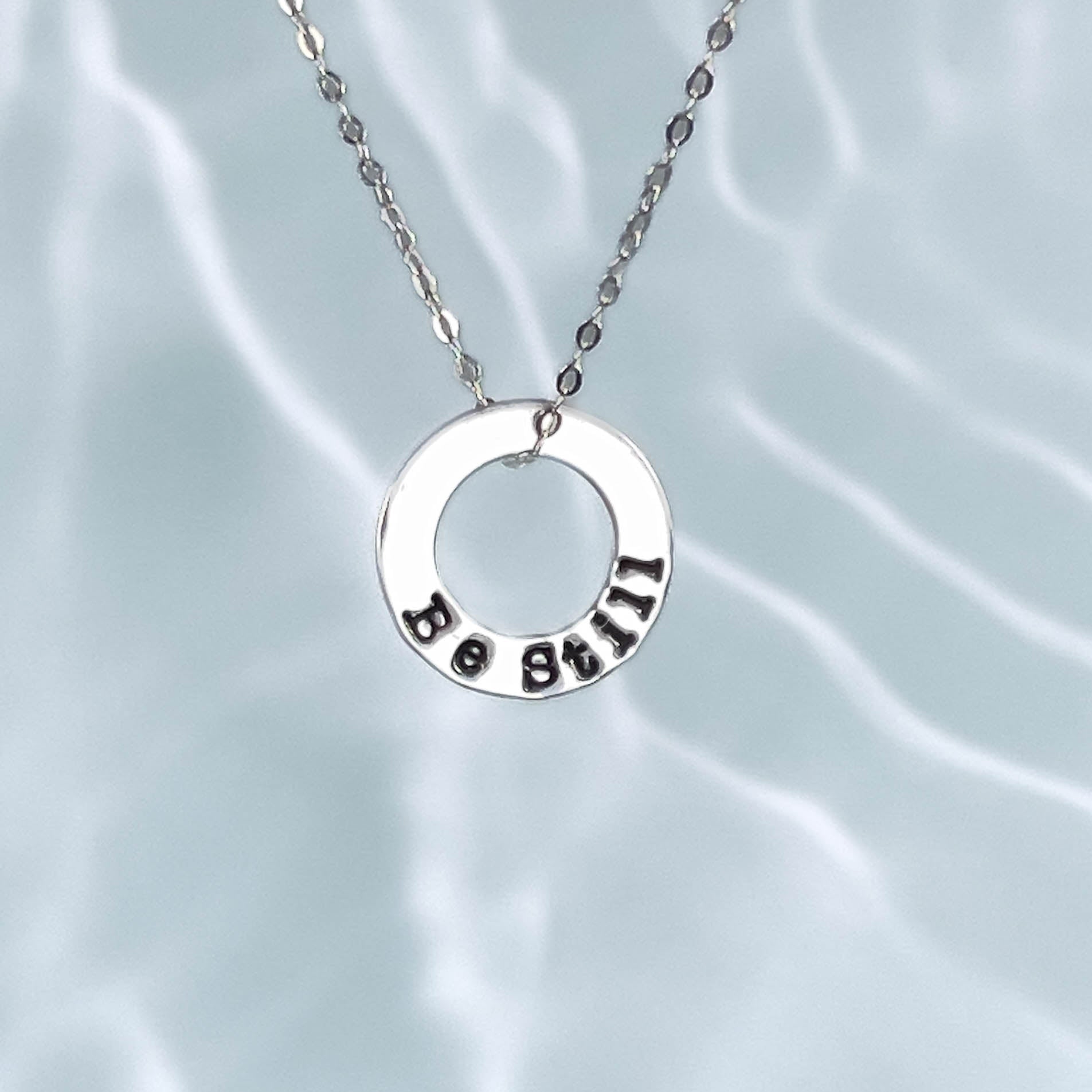 Silver necklace with a circular pendant on a light gray background