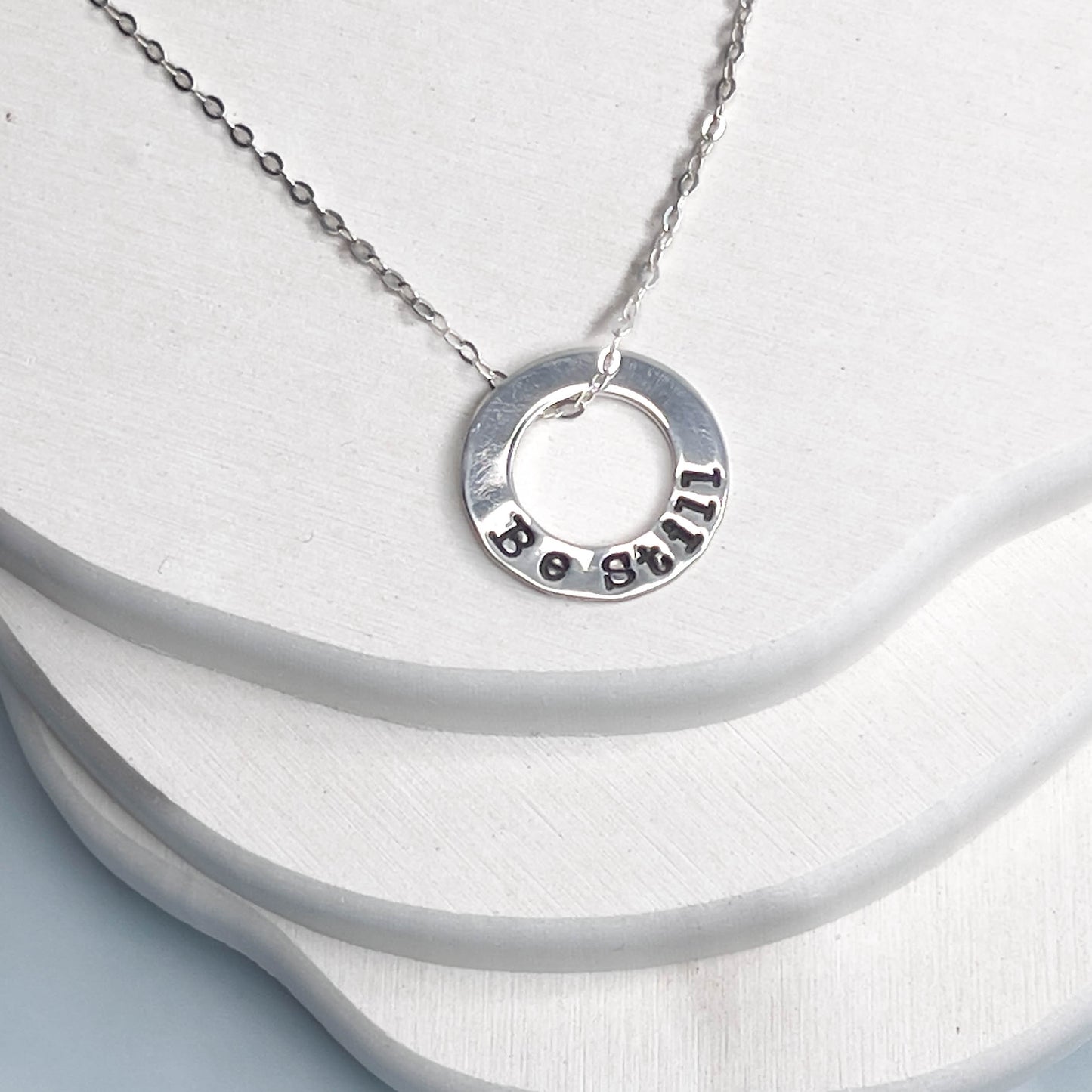 Silver necklace with a circular pendant on a white background