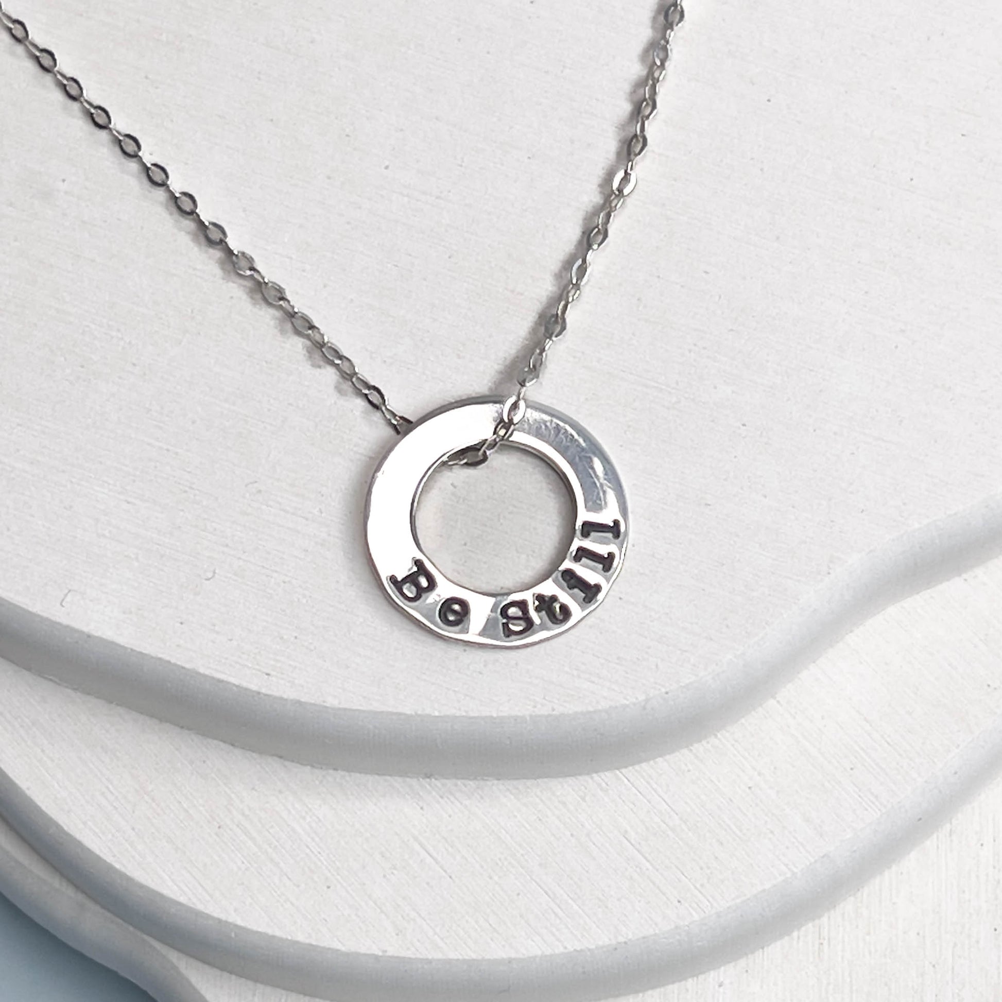 Silver necklace with a round pendant on a white background