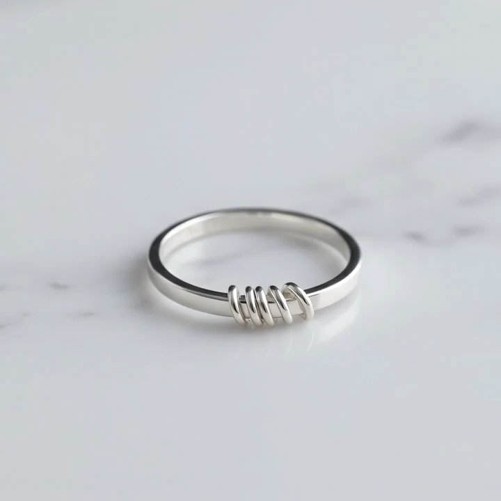 Silver fidget ring with a 5 outside spinner rings on a light gray background
