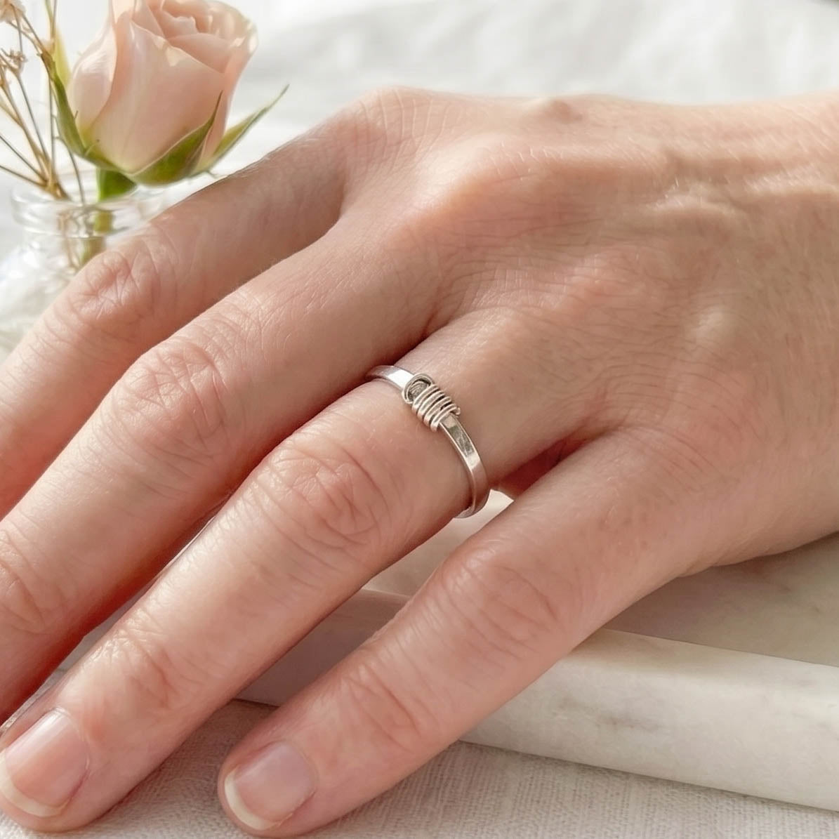 Hand wearing a sterling silver fidget ring with a soft focus background