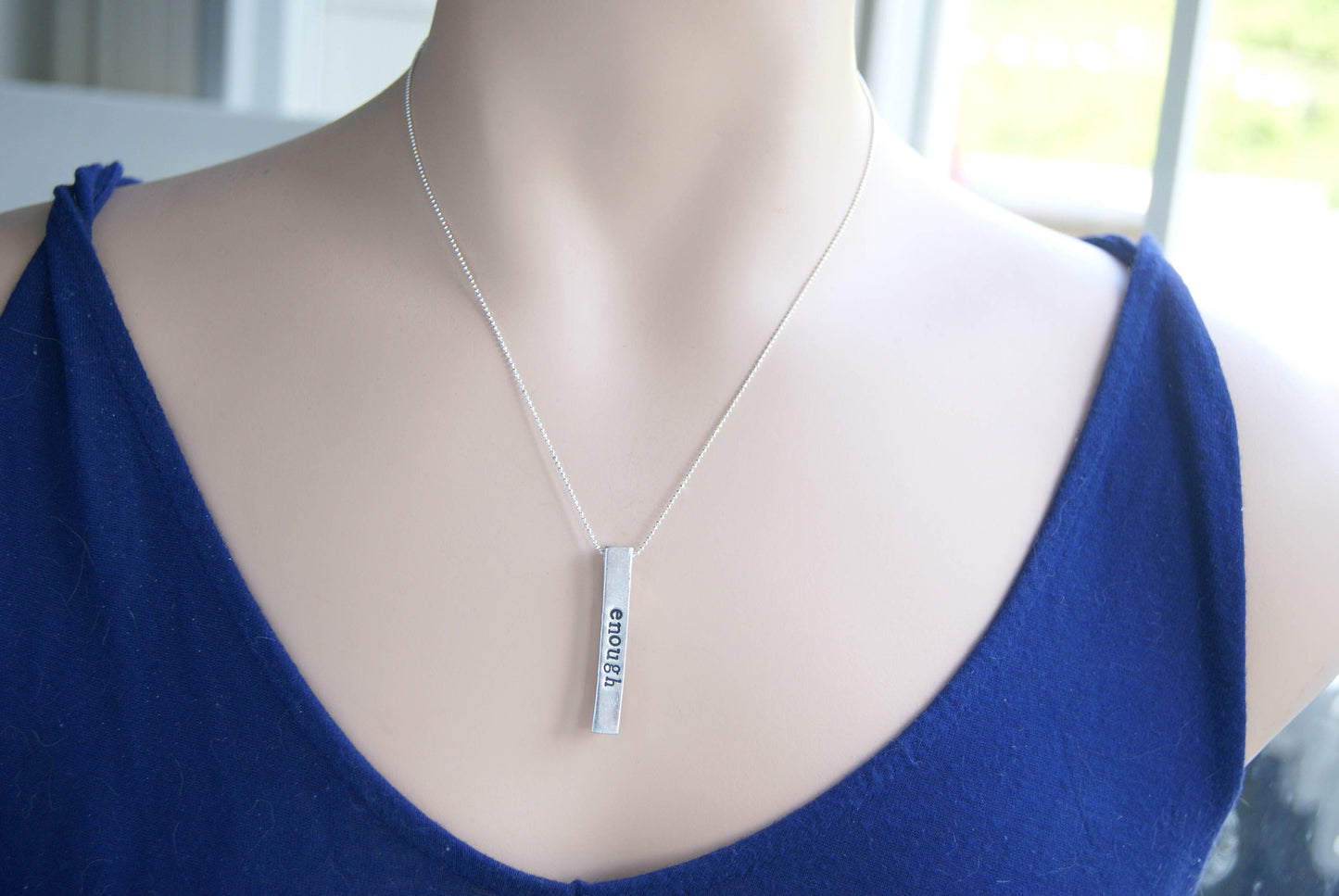 Long bar necklace stamped with strong, brave, and enough in artisan pewter on neck