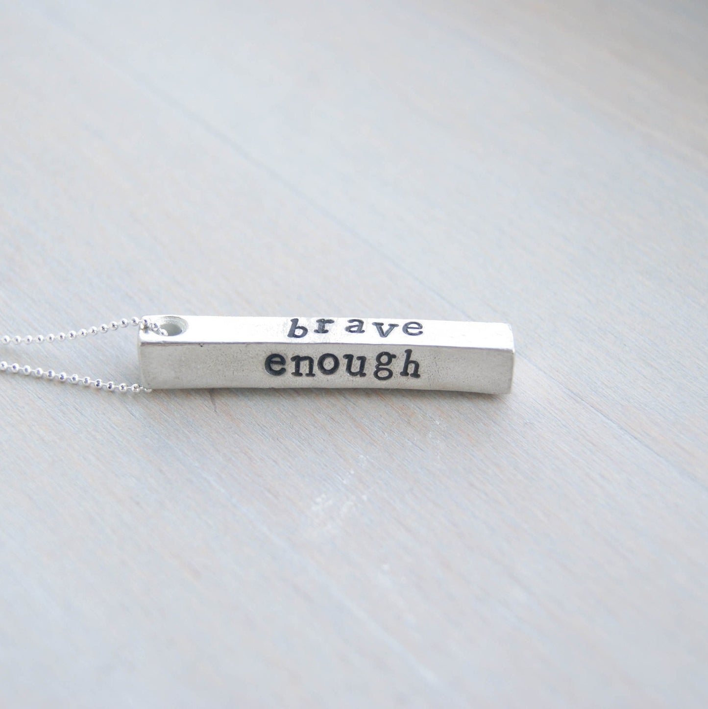 Long bar necklace stamped with strong, brave, and enough in artisan pewter