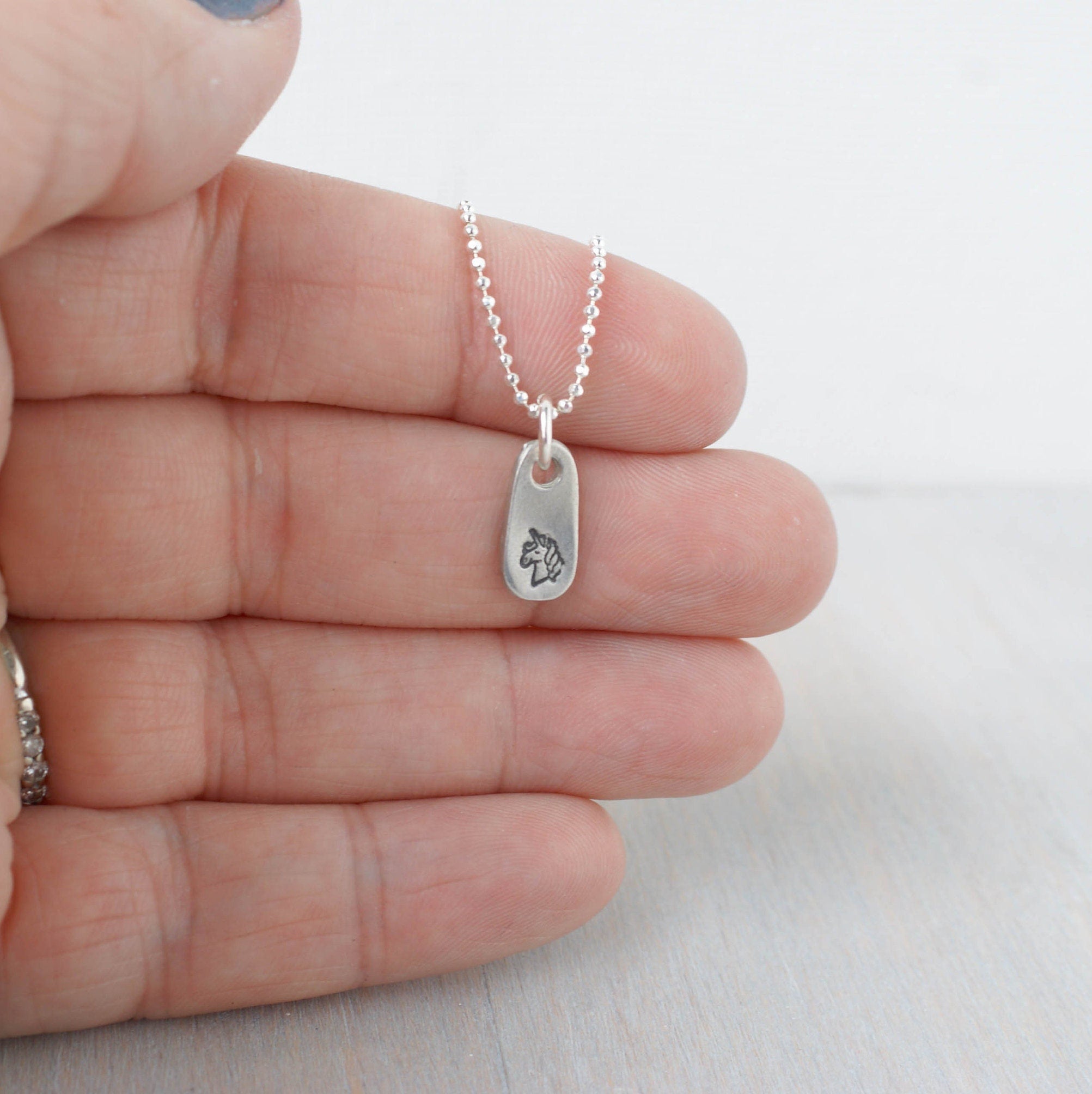 Silver unicorn necklace in artisan pewter in hand