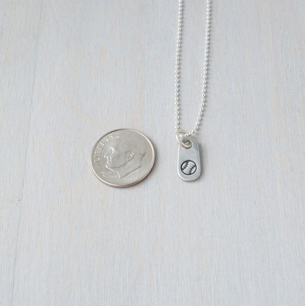 Silver baseball necklace in artisan pewter next to dime