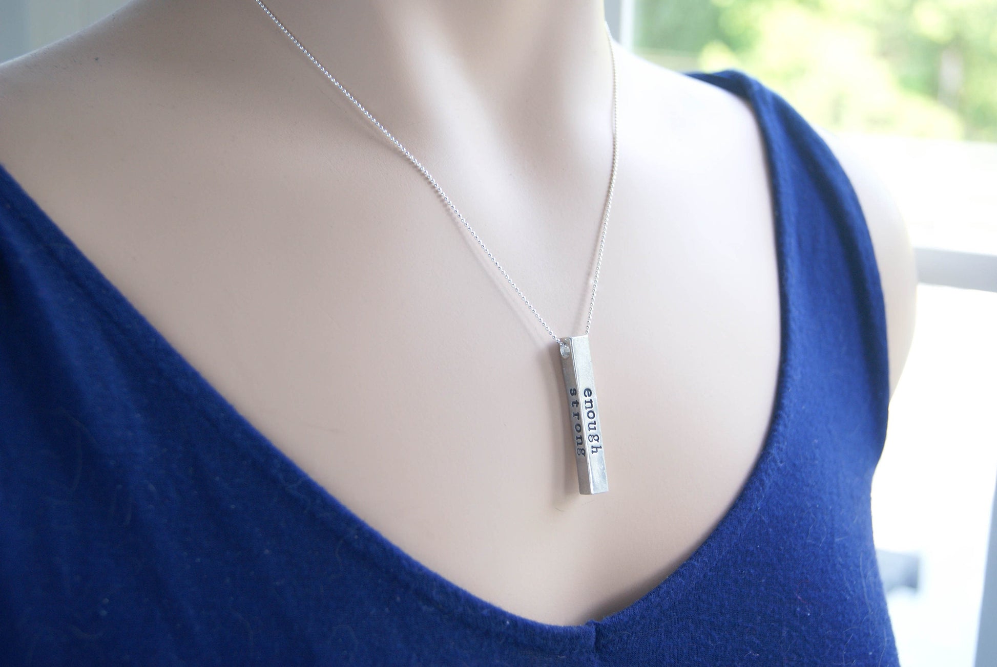 Long bar necklace stamped with strong, brave, and enough in artisan pewter on neck