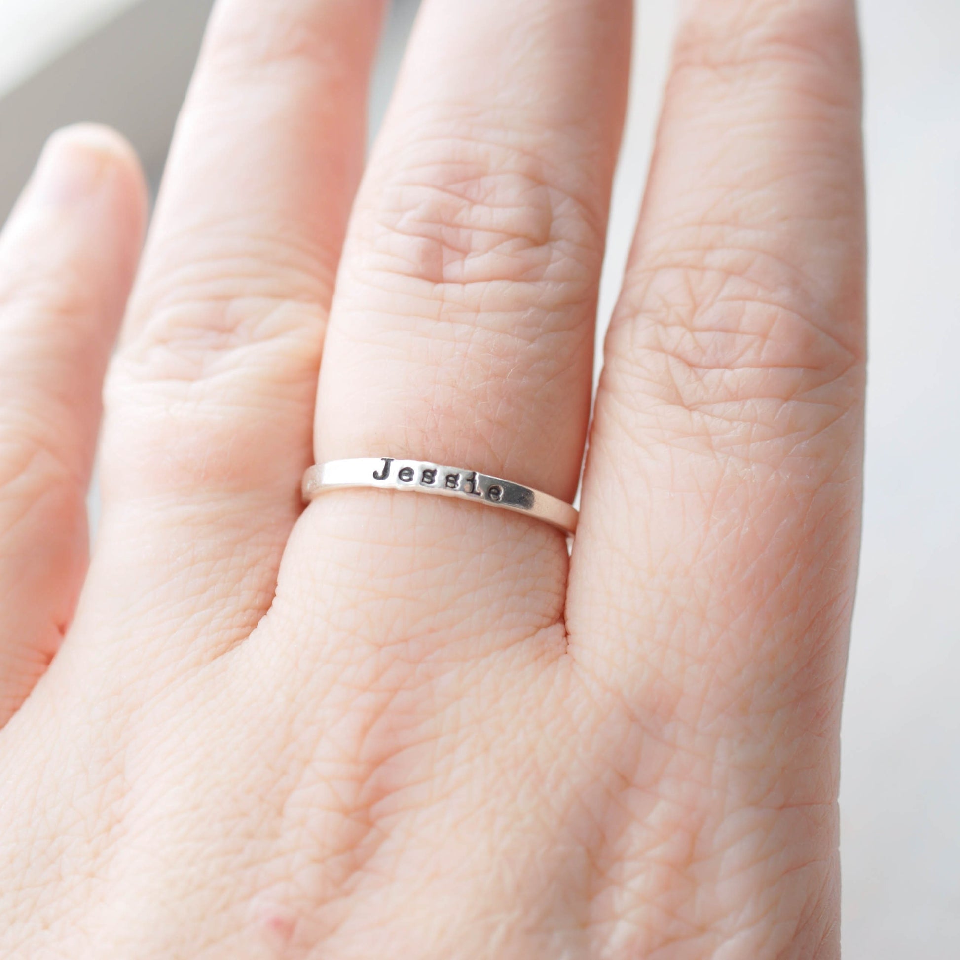 Sterling silver ring stamped with a personalized name on hand