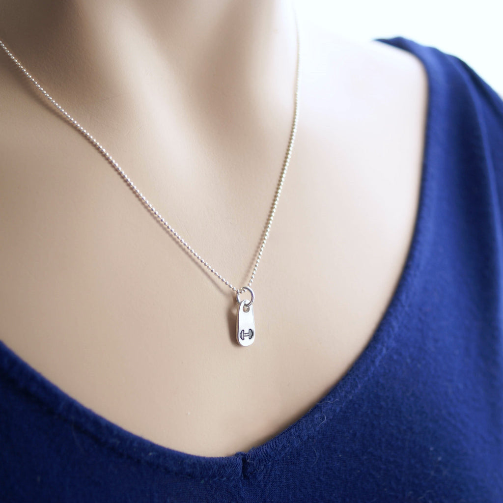 Silver dumbbell necklace for weightlifter in artisan pewter in hand