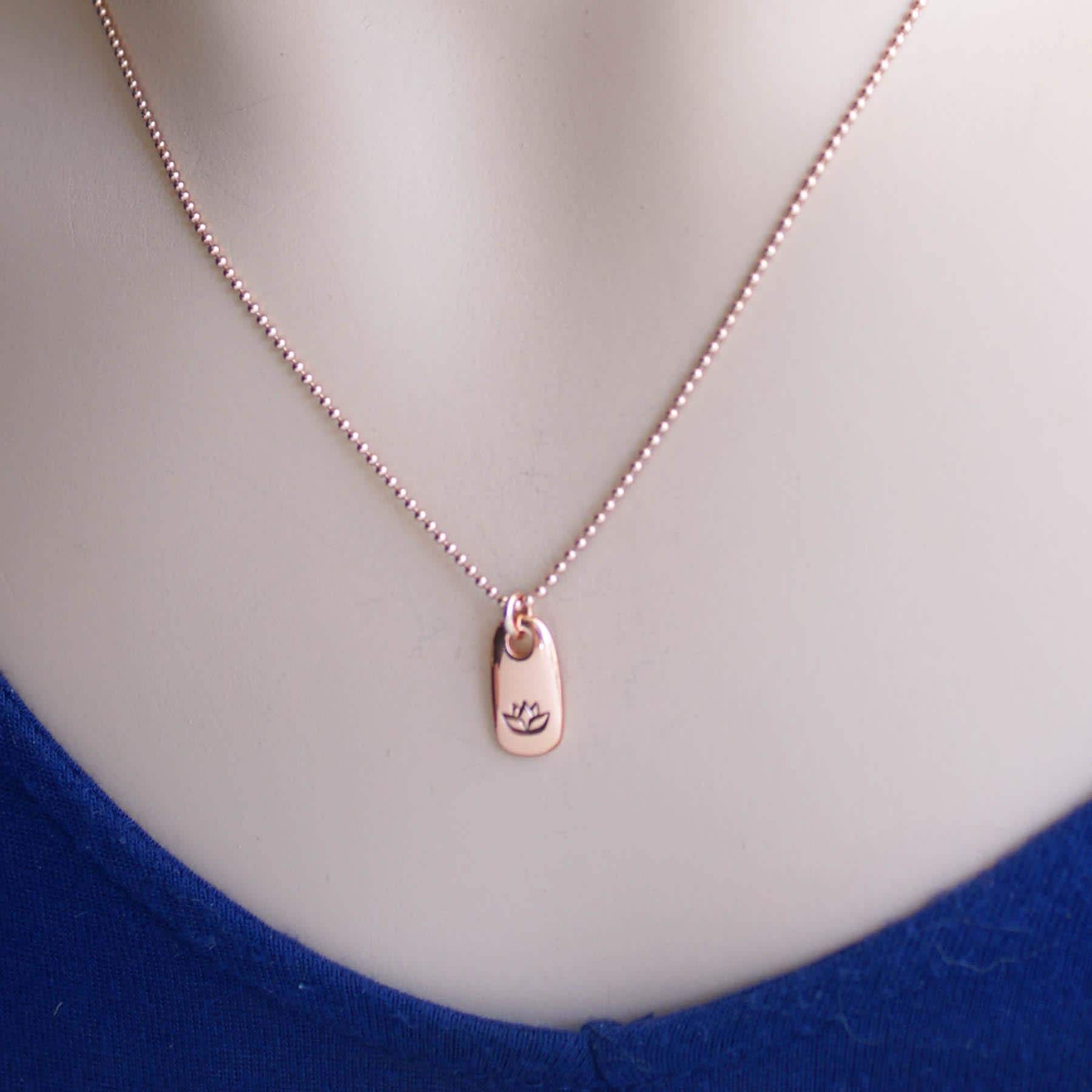 Image of Rose gold small tag necklace stamped with lotus flower on neck