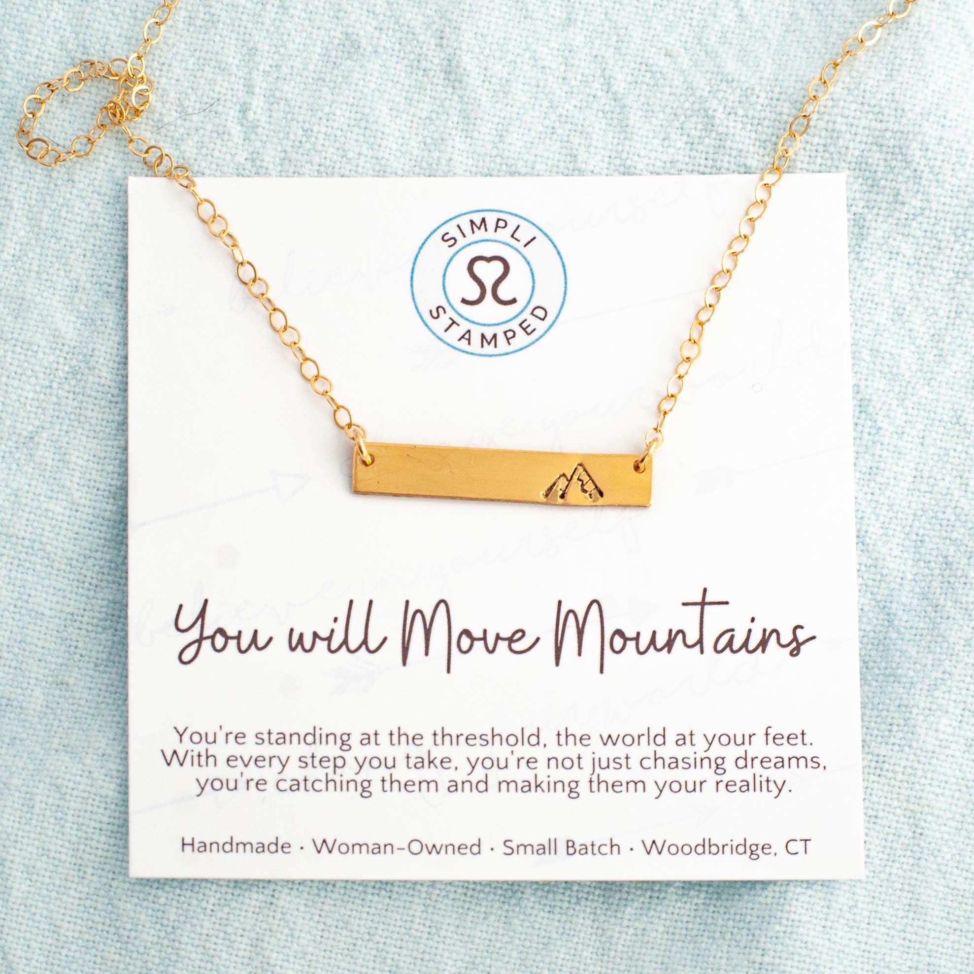 Image of gold necklace with mountain stamped on the right side on card with motivational card.