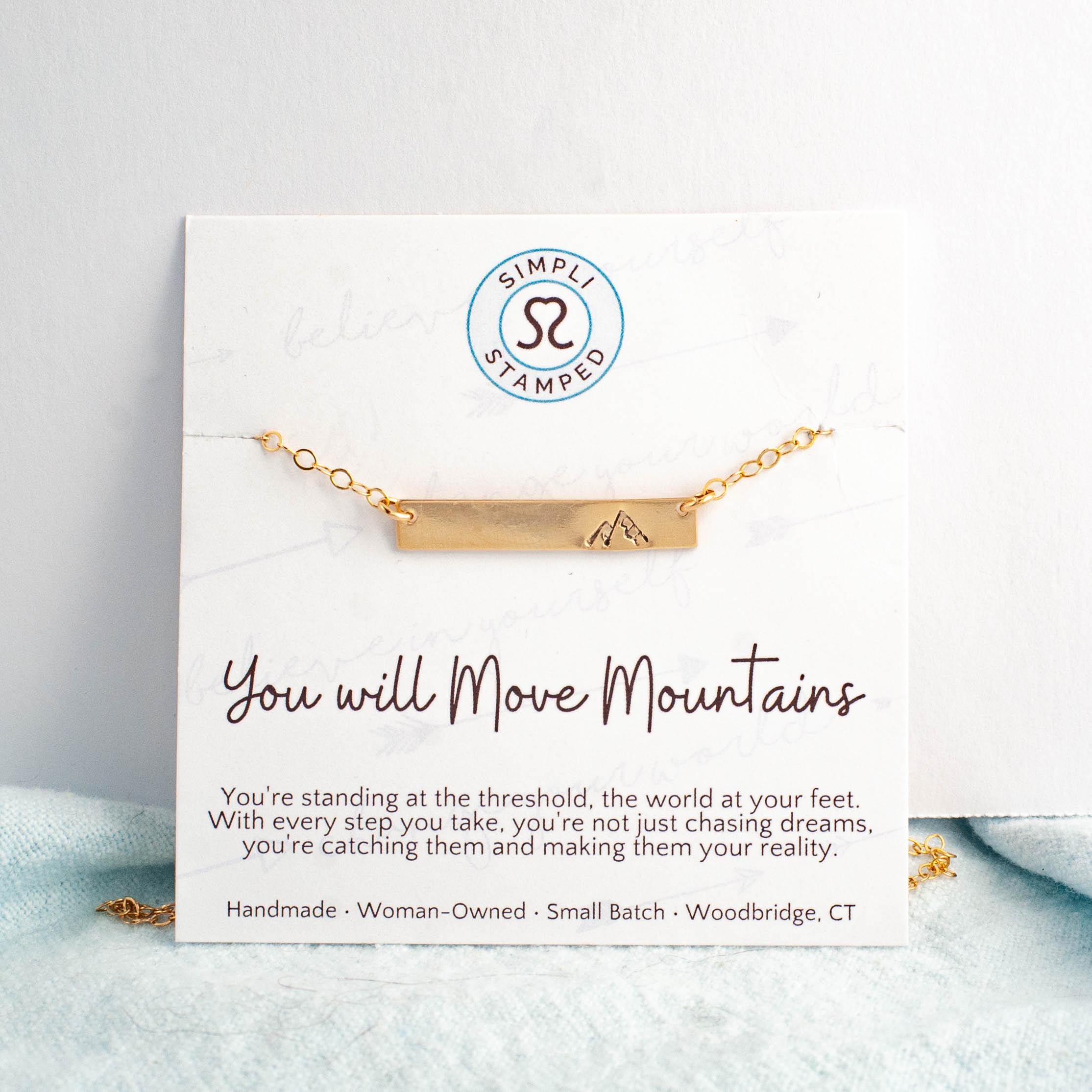 Image of gold necklace with mountain stamped on the right side on card with motivational card.