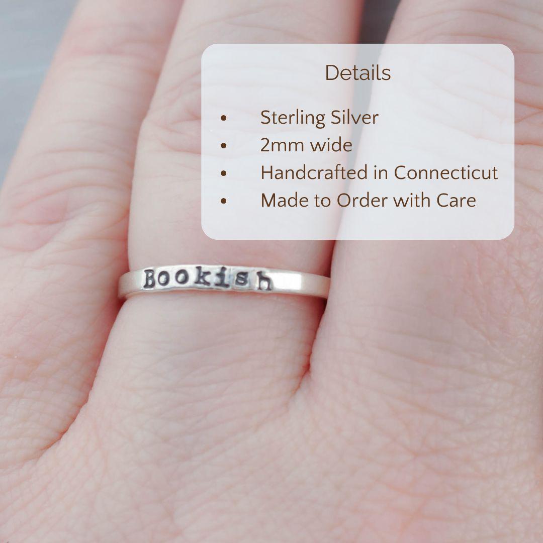 Image of Bookish ring on a hand with the product details overlayed. Sterling silver, 2mm wide, handcrafted in connecticut, made to order with care.