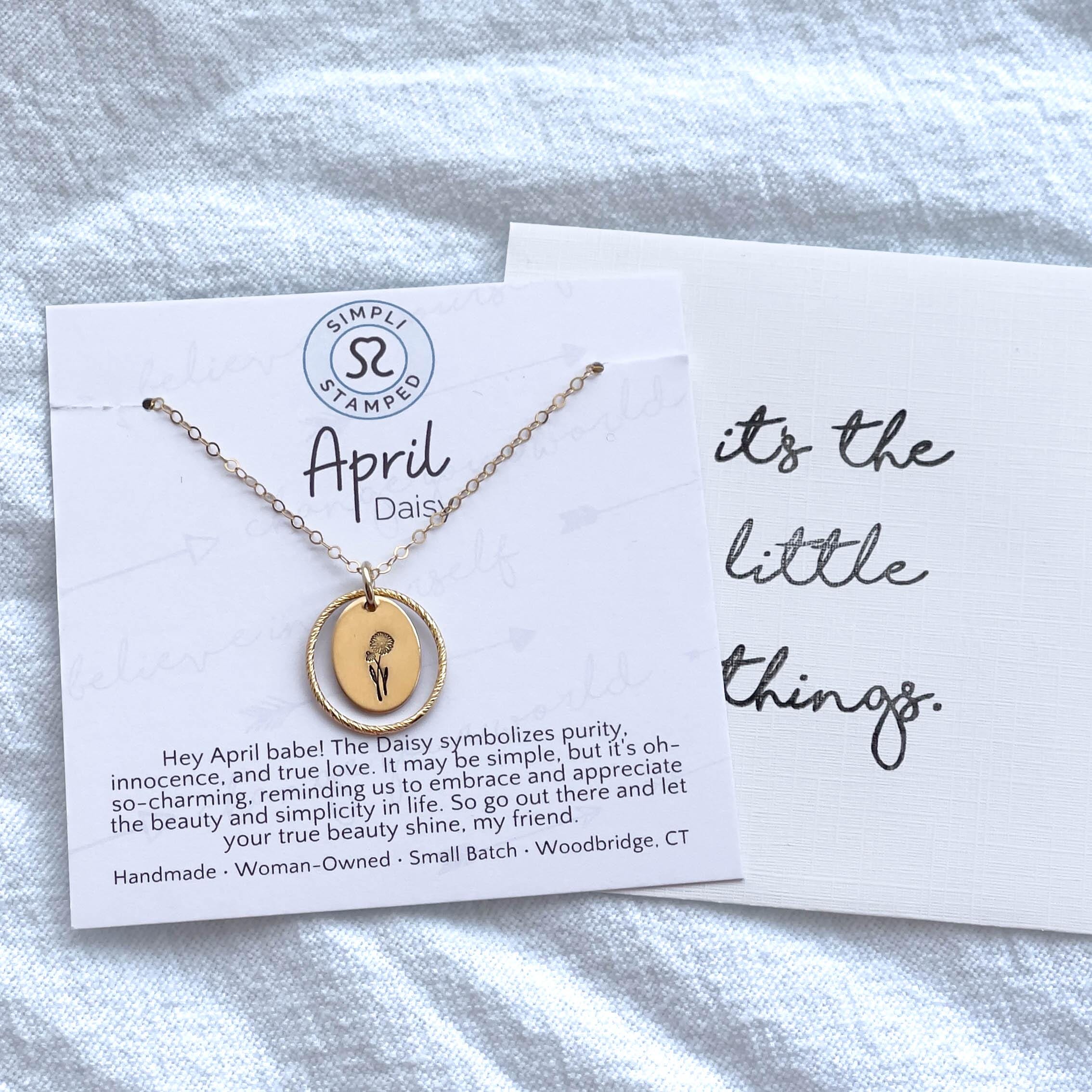 image of an oval gold birth flower necklace with a daisy stamped on it for april and a sparkle oval link surrounding it. the necklace is on a card that has an affirmation and says april