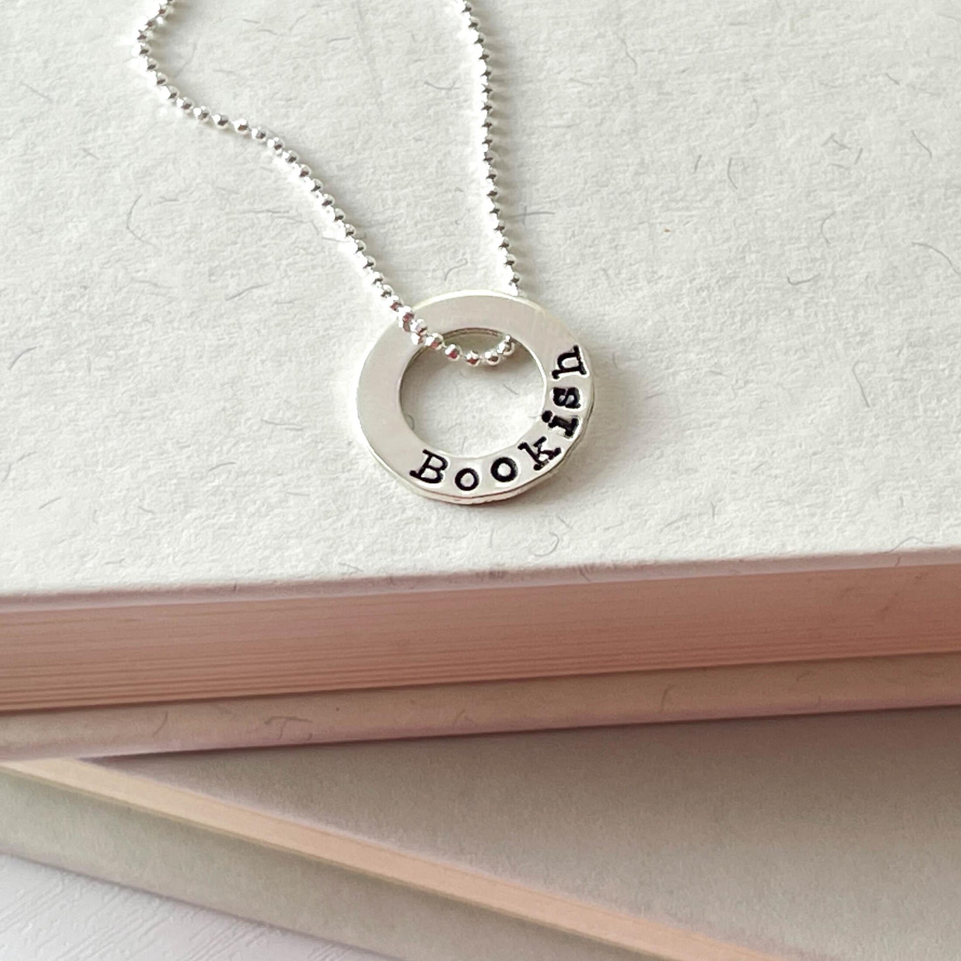 image of bookish sterling silver necklace laying on books