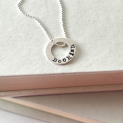 image of bookish sterling silver necklace laying on books