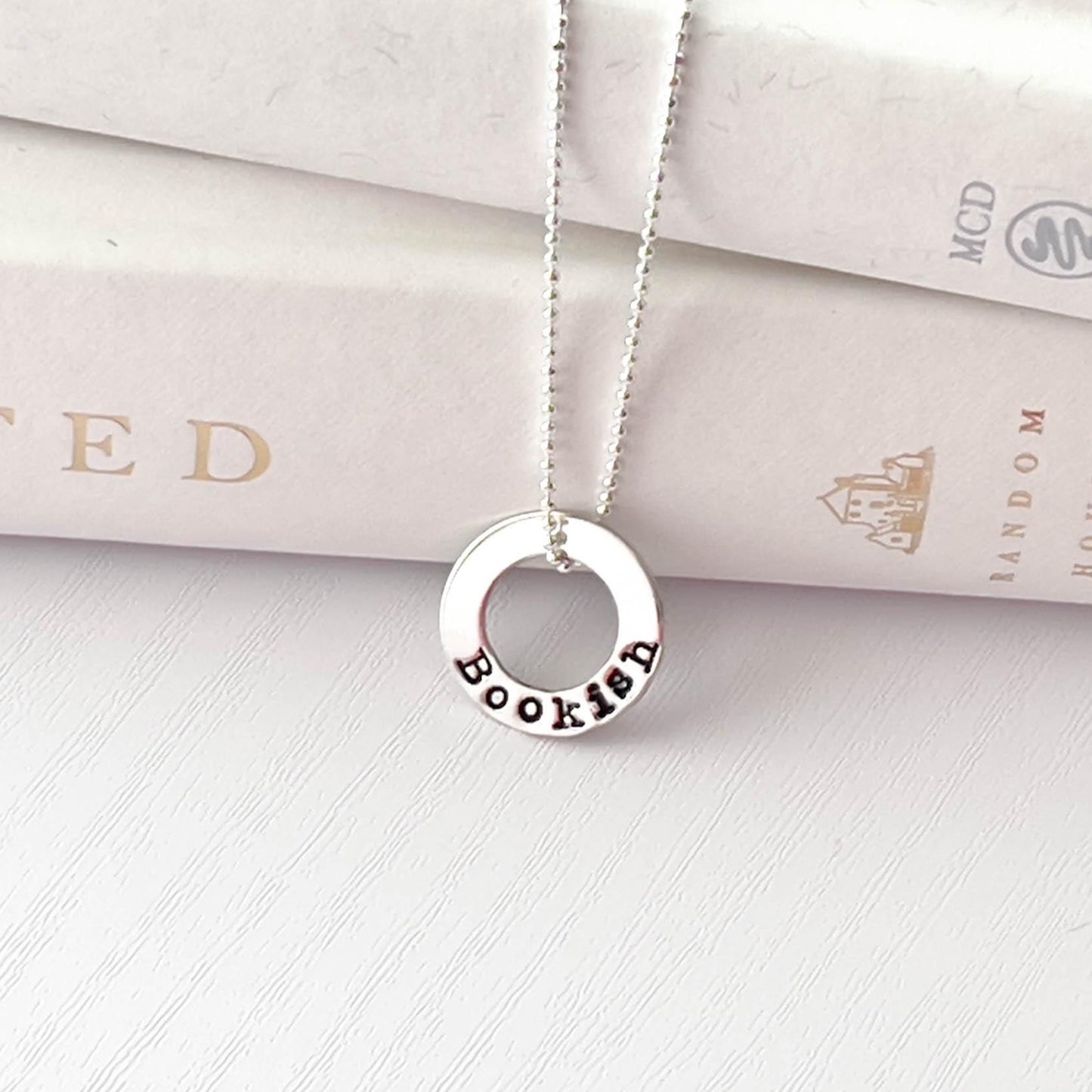 image of bookish sterling silver necklace leaning against books
