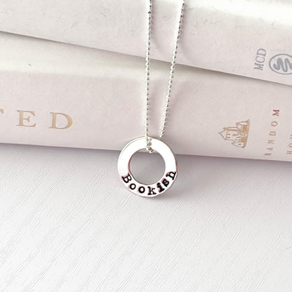 image of bookish sterling silver necklace leaning against books