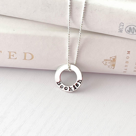 image of bookish sterling silver necklace leaning against books