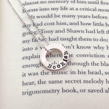 image of bookish sterling silver necklace laying on book page