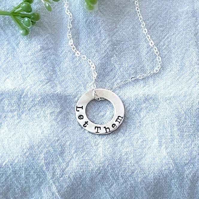 Sterling Silver Necklace stamped with Let Them on blue background