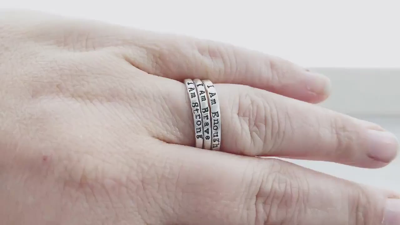 Three rings stacked, stamped with I Am Enough, I Am Strong, I Am Brave on hand