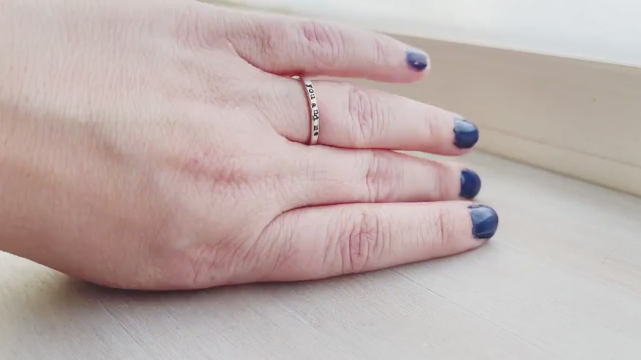 Skinny sterling silver ring stamped with you and me on hand and being held