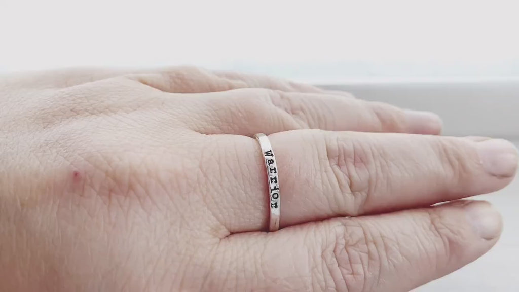 Sterling silver ring stamped with Warrior on hand and being held