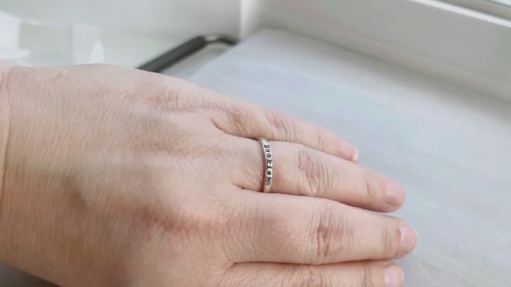 Bookish ring on a hand on a neutral background