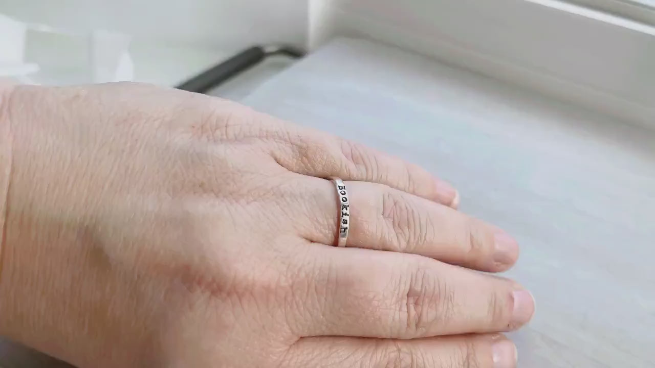 Bookish ring on a hand on a neutral background