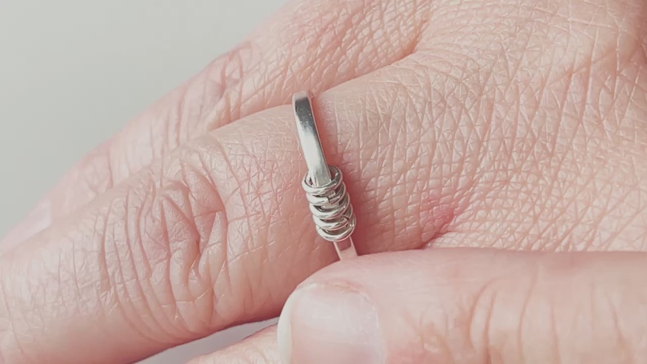 video of sterling silver fidget ring on hand with the outside rings being pushed back and forth