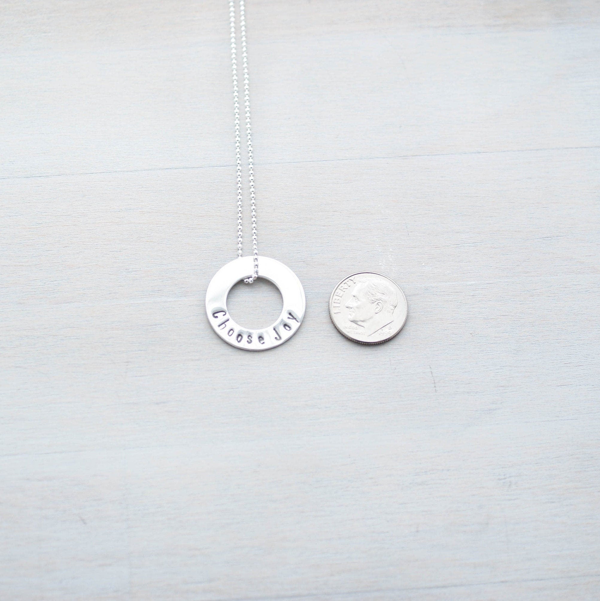 Choose Joy Circle Necklace in Sterling Silver next to dime for scale