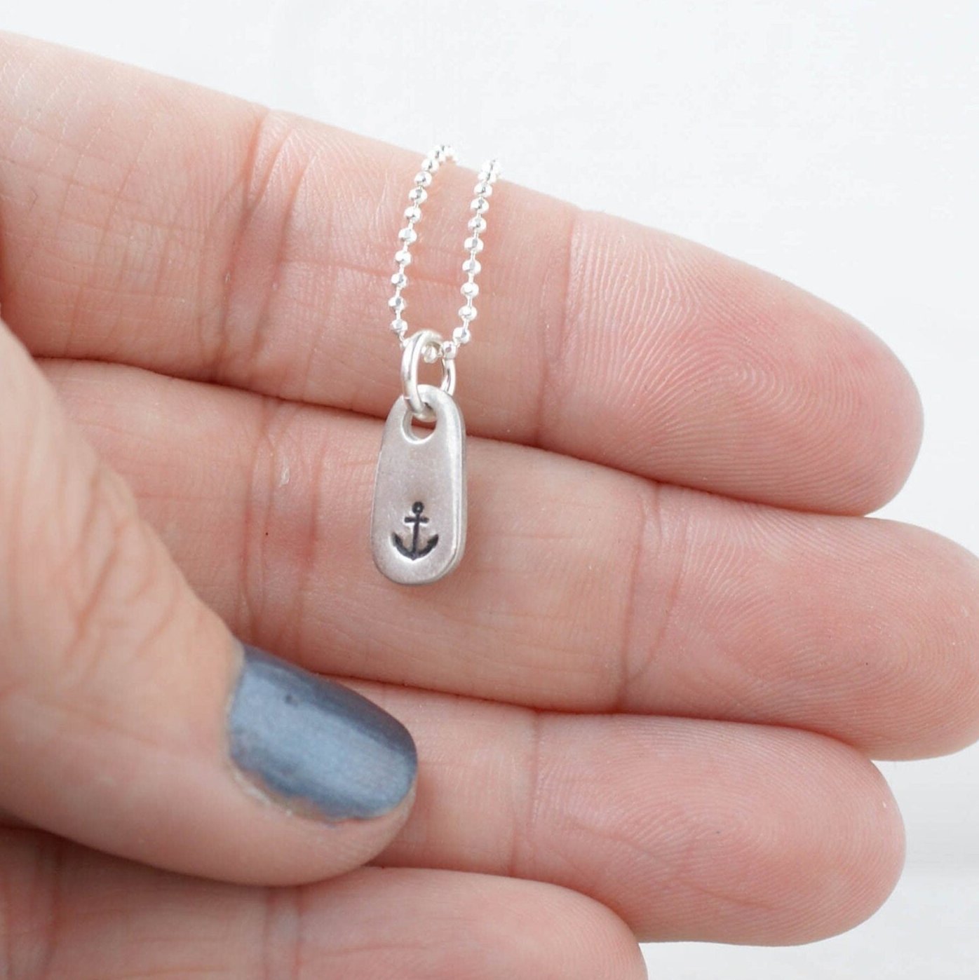 Anchor Necklace Refuse to Sink Strength NeDainty Handstamped Anchor Necklace in Pewter being held in hand for scale