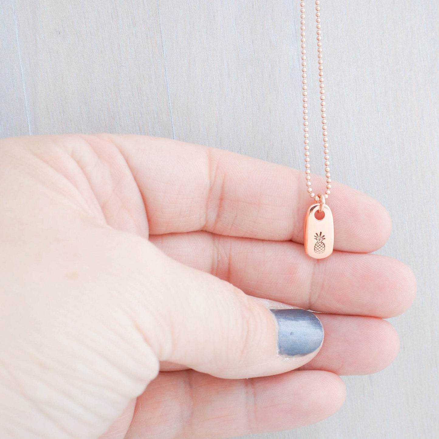 Dainty rose gold pineapple necklace in hand