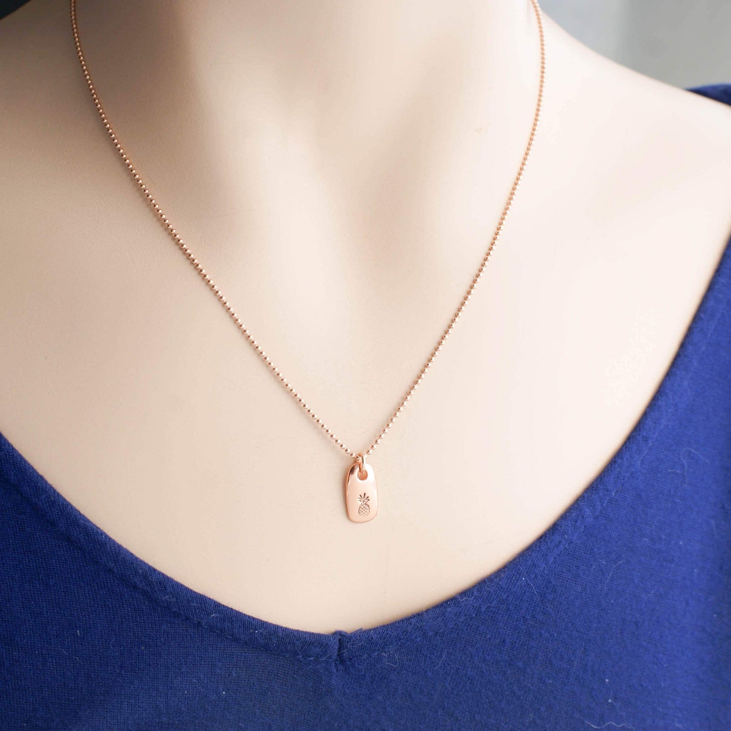 Dainty rose gold pineapple necklace on neck