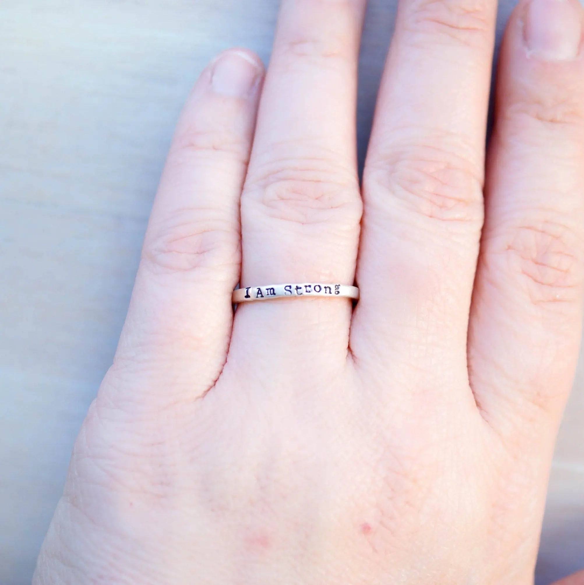 Sterling Silver stacking ring handstmaped with I Am Strong on hand