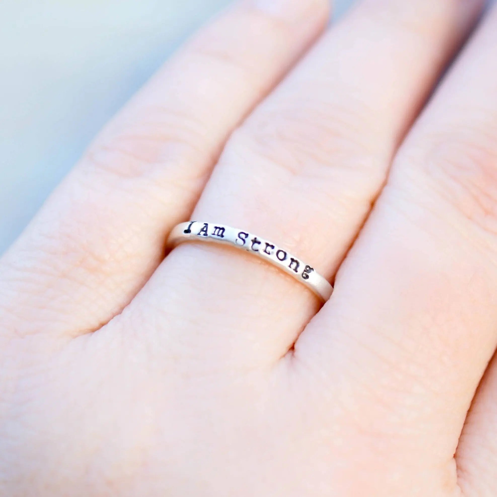 Sterling Silver ring stamped with I Am Strong on hand