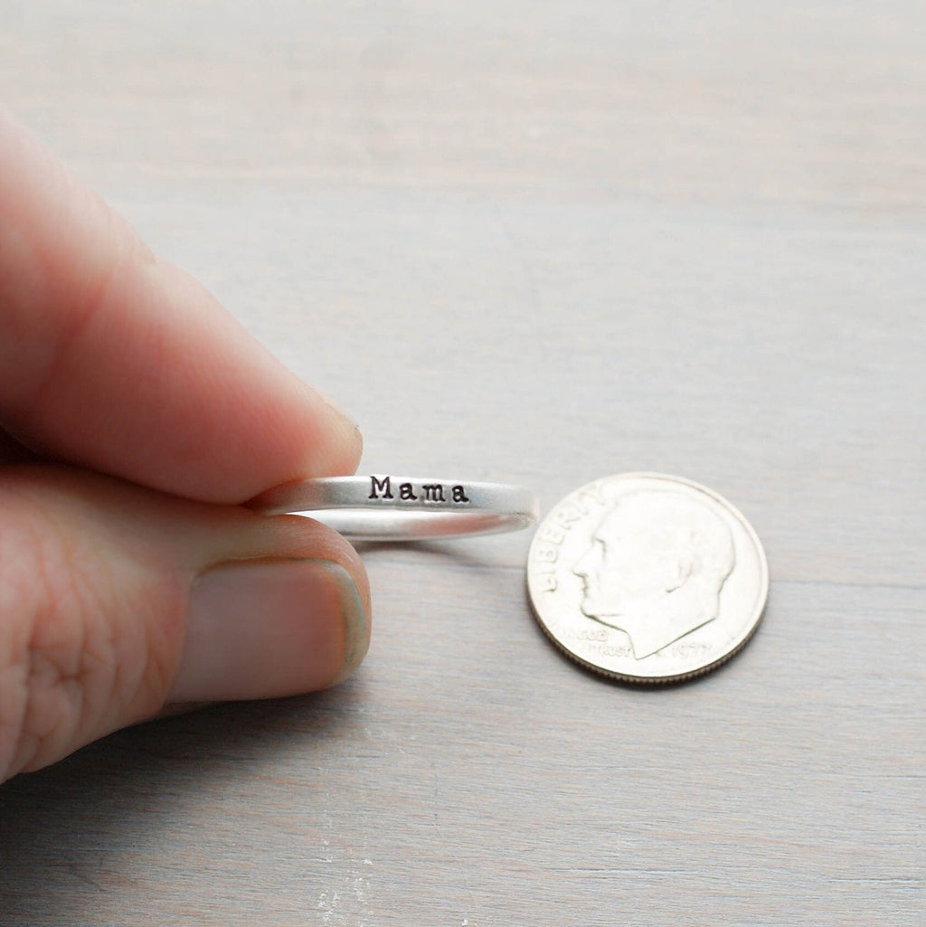 Sterling silver ring handstamped with Mama held between fingers