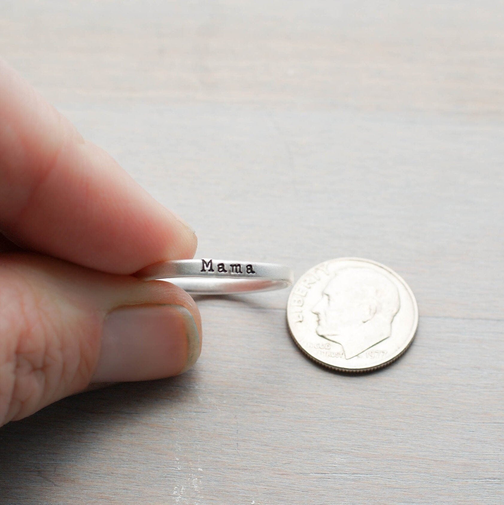 Sterling silver ring handstamped with Mama held between fingers