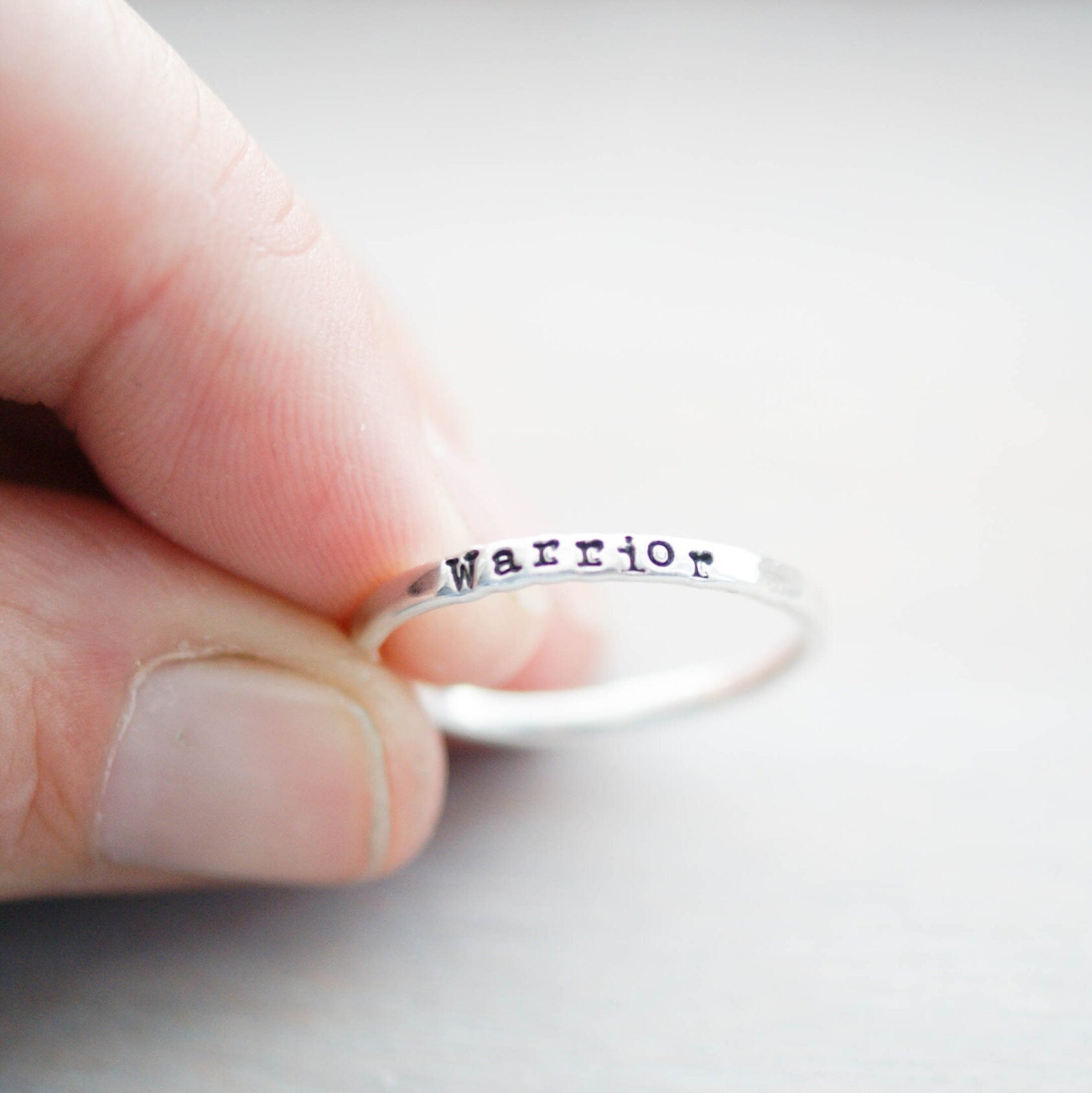 Sterling silver ring stamped with Warrior between fingers