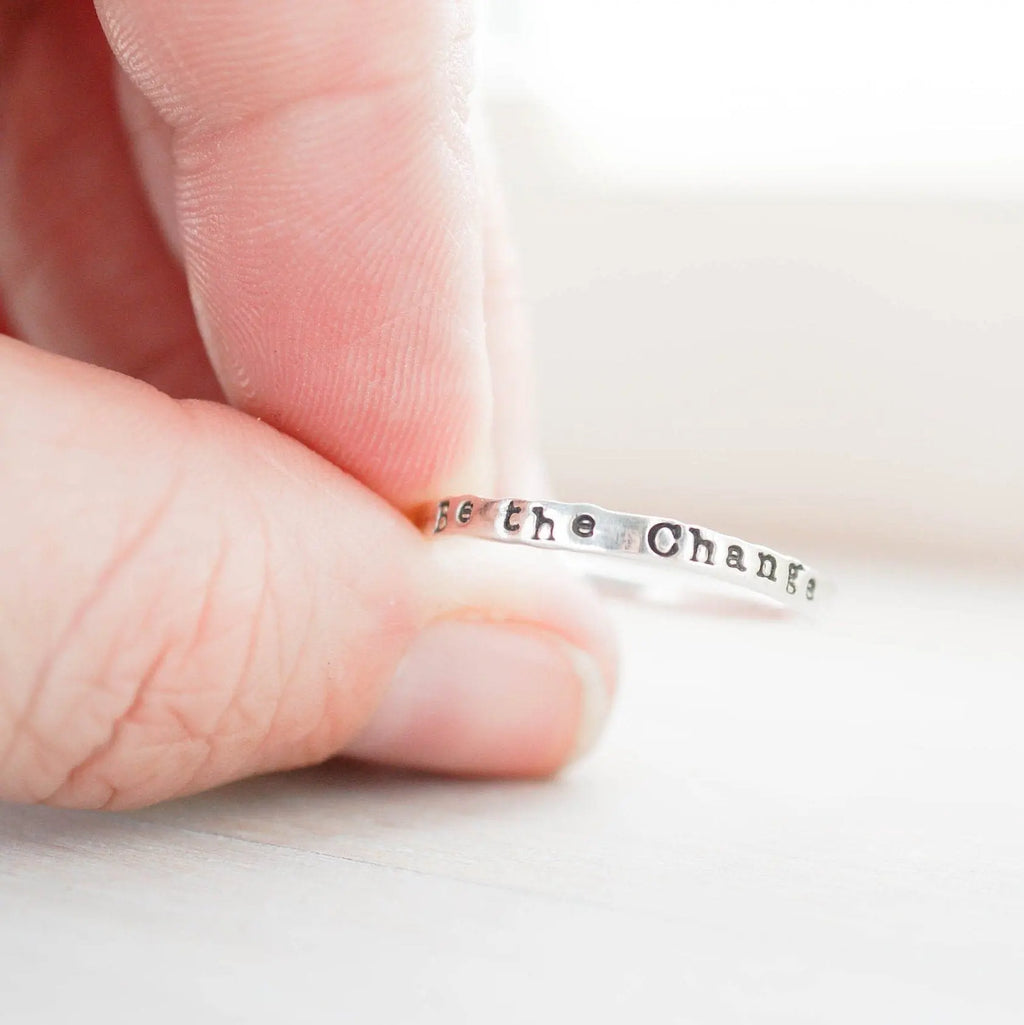 Be the Change Ring Stackable Skinny Thin Ring Be Positive Motivational Jewelry held between fingers