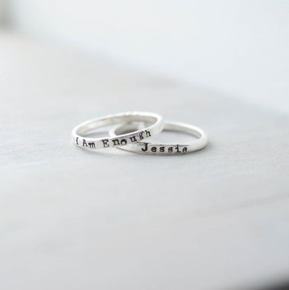 Sterling silver ring stamped with a personalized name with a second ring stamped with I Am Enough