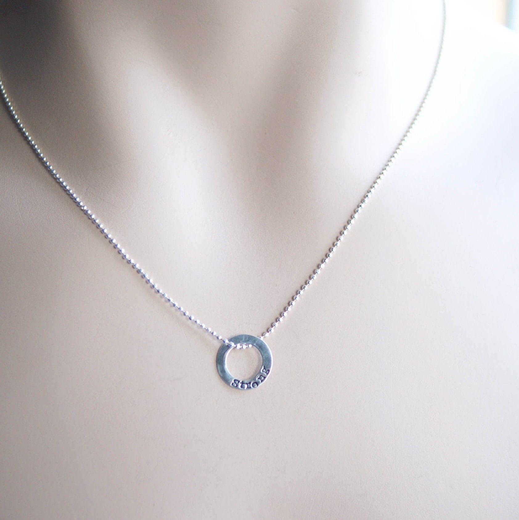 Sterling silver tiny circle stamped with Strong necklace on neck