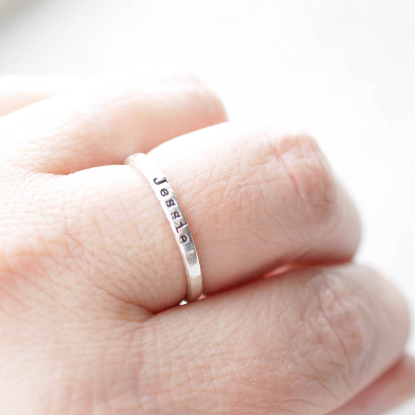 Sterling silver ring stamped with a personalized name on hand